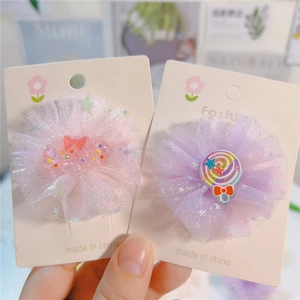 Détail de pinces à cheveux fleurs en tulle avec bonbons pailletés et sucette arc-en-ciel
