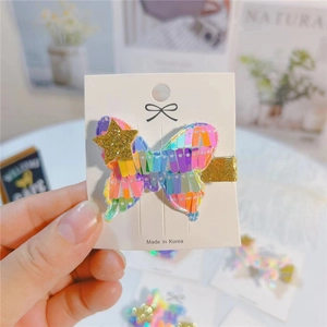 Colorful sequin butterfly hair clip with gold star detail for girls on a display card