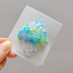 Détail d'une pince à cheveux glace avec tulle bleu et paillettes sur carte blanche