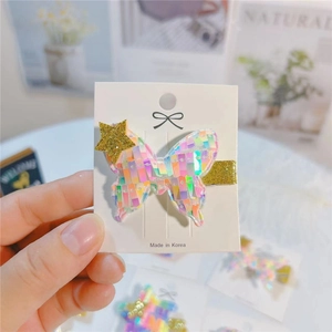 Handheld butterfly hair clip with iridescent sequins and gold star on white display card