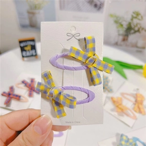 Close-up of set of two purple hair clips with yellow and grey plaid fabric bows