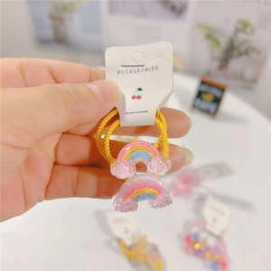 Detail of yellow spiral hair tie with glittery rainbow charms for young girls