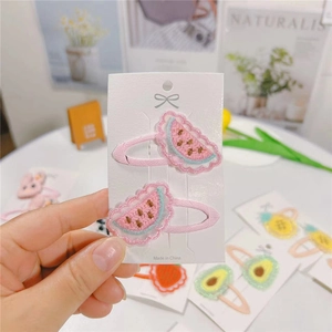 Close-up of handmade embroidered watermelon hair clip with soft pink ribbon lining