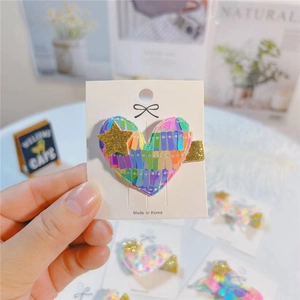 Detail of colorful sequined heart hair clip with a gold glitter star on display card