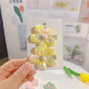 Détail de deux barrettes fleurs jaunes à paillettes avec perles sur carte support