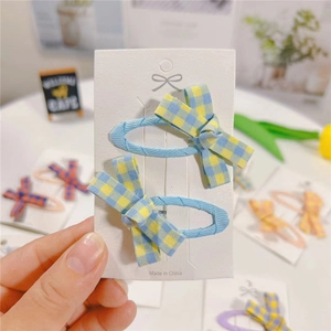 Set of two sky blue plaid fabric bow hair clips for girls on a white display card