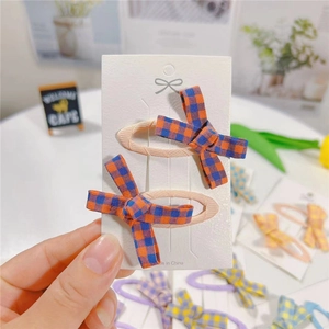 Set of two pink fabric bow hair clips with orange and blue plaid pattern for girls
