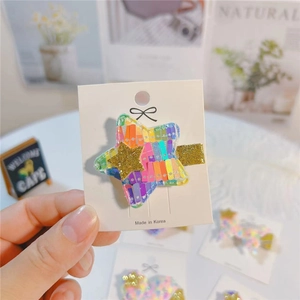 Macro shot of colorful rainbow star hair clip with gold glitter center on card