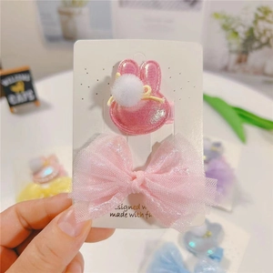 Détail de pince à cheveux lapin rose et nœud en maille sur support cartonné pour enfant