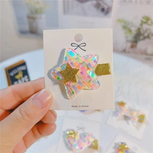Close-up of glitter star hair clip with iridescent mosaic pattern on display card
