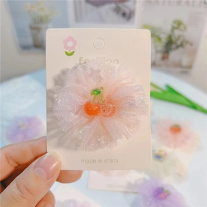 Vue détaillée d'une pince à cheveux fleur en maille rose avec cerise sur carte