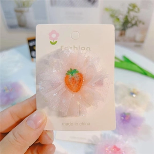 Détail d'une pince à cheveux fleur en tulle rose avec petite fraise pour petites filles