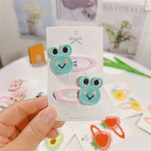 Detail view of handmade knitted frog hair clips for kids with soft fabric wrapping