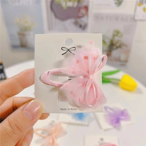 Detail of pink mesh bow hair clip with red polka dots and satin ribbon on white card