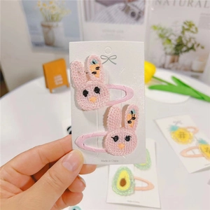 Detailed close-up of cute pink embroidered rabbit hair clips for children on display card