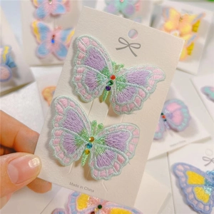 Close-up of embroidered butterfly hair clips with colorful rhinestones on display card