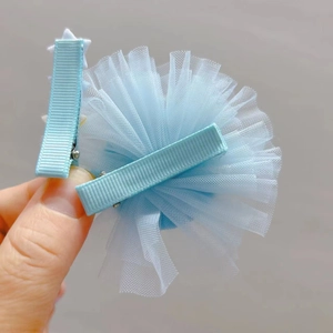 Détail de barrettes pompons en tulle bleu et accessoires en ruban étoile pour filles
