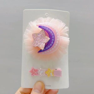 Détail de barrettes en tulle rose avec étoiles et lune pailletées pour filles