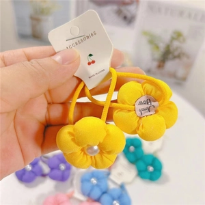 Détail d'un élastique à fleurs en coton jaune avec perle centrale pour filles