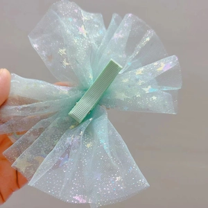 Detail of light green mesh bow hair clip featuring colorful star sequins and ribbon wrap