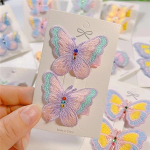Close-up of embroidered butterfly hair clips with colorful rhinestones on display card