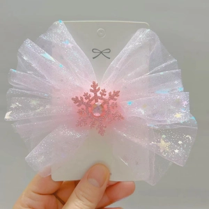 Detail of white tulle hair bow clip with silver star sequins and pink snowflake charm