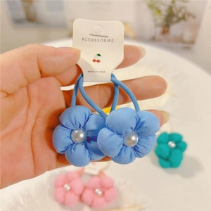Détail d'élastiques à cheveux fleurs en tissu bleu avec perles sur une carte en papier
