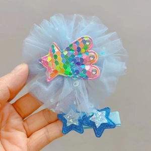Détail de pinces à cheveux en tulle bleu clair avec paillettes arc-en-ciel et étoiles