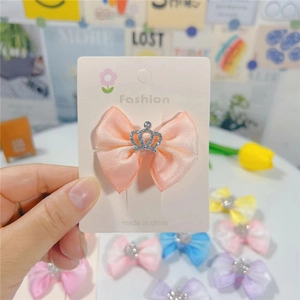 Détail de la pince à cheveux nœud rose pêche avec couronne argentée pour filles