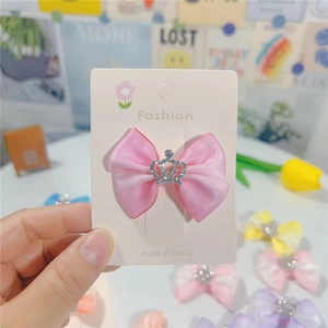 Détail d'une pince à cheveux à nœud en satin rose avec couronne argentée scintillante