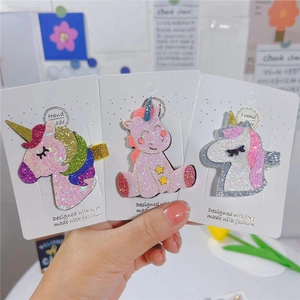 Détail de trois barrettes licorne à paillettes sur une carte de présentation blanche
