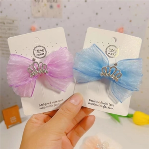 Détail de barrettes à nœuds en organza bleu et violet avec couronnes en strass