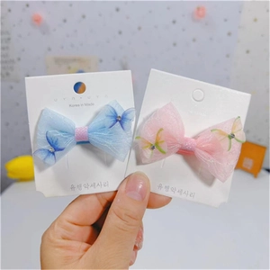 Vue détaillée des pinces à cheveux papillon en dentelle rose et bleue avec sequins brillants