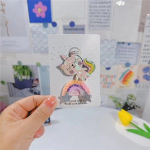 Détail de barrettes à paillettes licorne chat et arc-en-ciel sur carte avec des tulipes