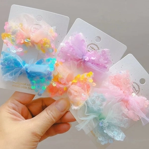 Dettaglio di fermagli per capelli con fiocchi in tulle e paillettes in colori pastello