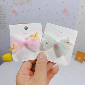 Détail de barrettes papillon en tulle rose et vert avec strass sur carte blanche