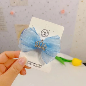 Vue détaillée d'une pince à cheveux en organza bleu clair ornée d'une couronne en strass