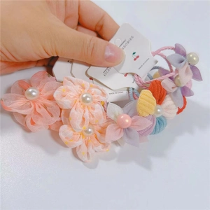 Detail eines Blumen-Haargummis aus Stoff mit Perle und Zubehörkarte für Mädchen