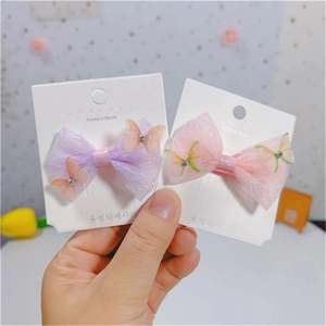 Détail de barrettes nœuds en maille rose et violette avec papillons pailletés et strass