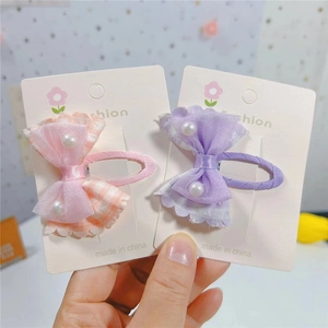 Détail de barrettes nœuds en gaze à carreaux rose et violet avec perles blanches