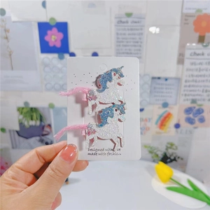 Détail de deux barrettes licorne à paillettes avec glands roses sur une carte