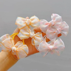 Detail of six organza bow hair clips and ties featuring polka dots and orange trim