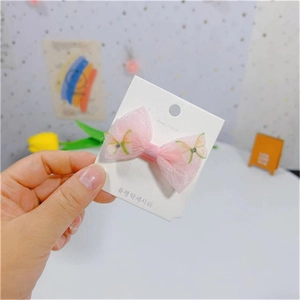 Gros plan sur une pince à cheveux nœud en résille rose avec papillon et strass brillants