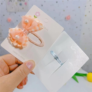 Détail de la pince à cheveux noeud à carreaux rose avec perles et clip en métal