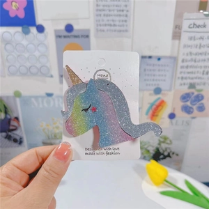 Détail d'une pince à cheveux licorne arc-en-ciel à paillettes avec corne dorée sur carte