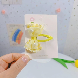 Détail d'une barrette à cheveux nœud à carreaux jaunes avec perles sur carte de support