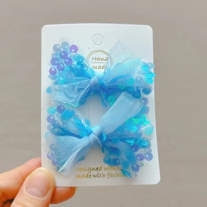 Dettaglio di fermagli per capelli a fiocco con paillettes blu su scheda espositiva