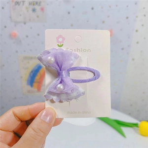 Gros plan d'une pince à cheveux avec nœud en dentelle violette et perles centrales