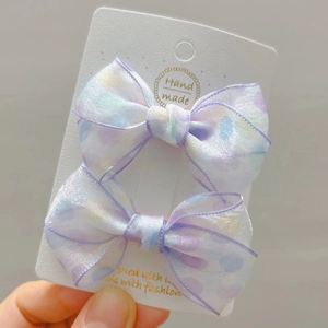 Close-up of handmade translucent mesh hair bows with colorful polka dots on card