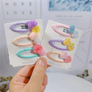 Dettaglio di fermagli per capelli con pompon colorati e cuori glitterati per bambine